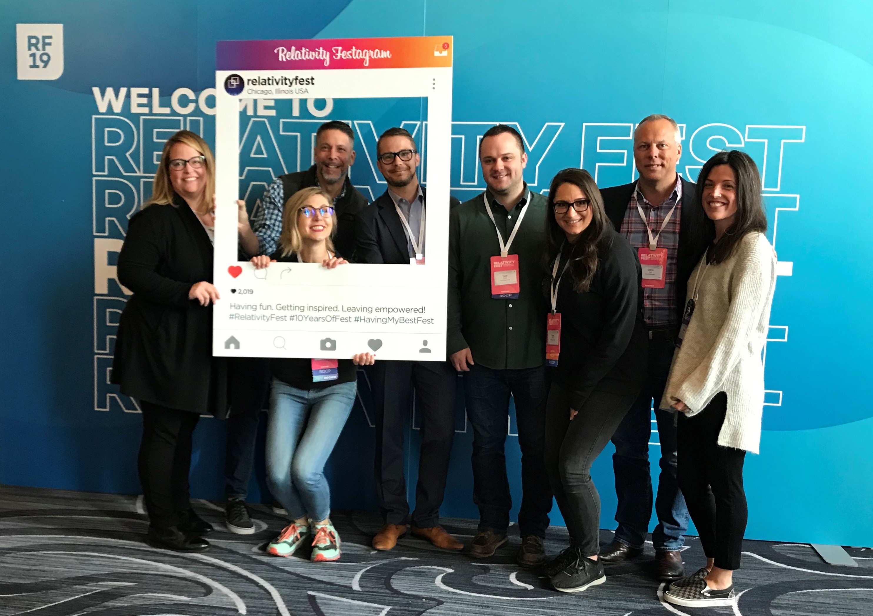 Members of JND eDiscovery team pose for photo at Relativity Fest 2019 marquee.